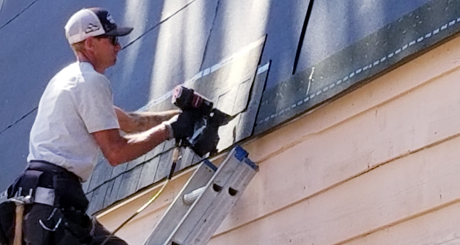 Roofer nailing shingles on a steep mansard roof